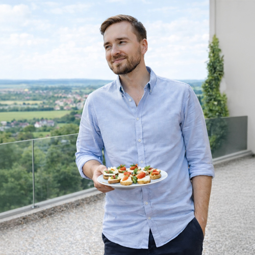 Bild eines Stonelli Testimonials welches Mann mit Canapes auf stonelli steinteppich terasse zeigt.