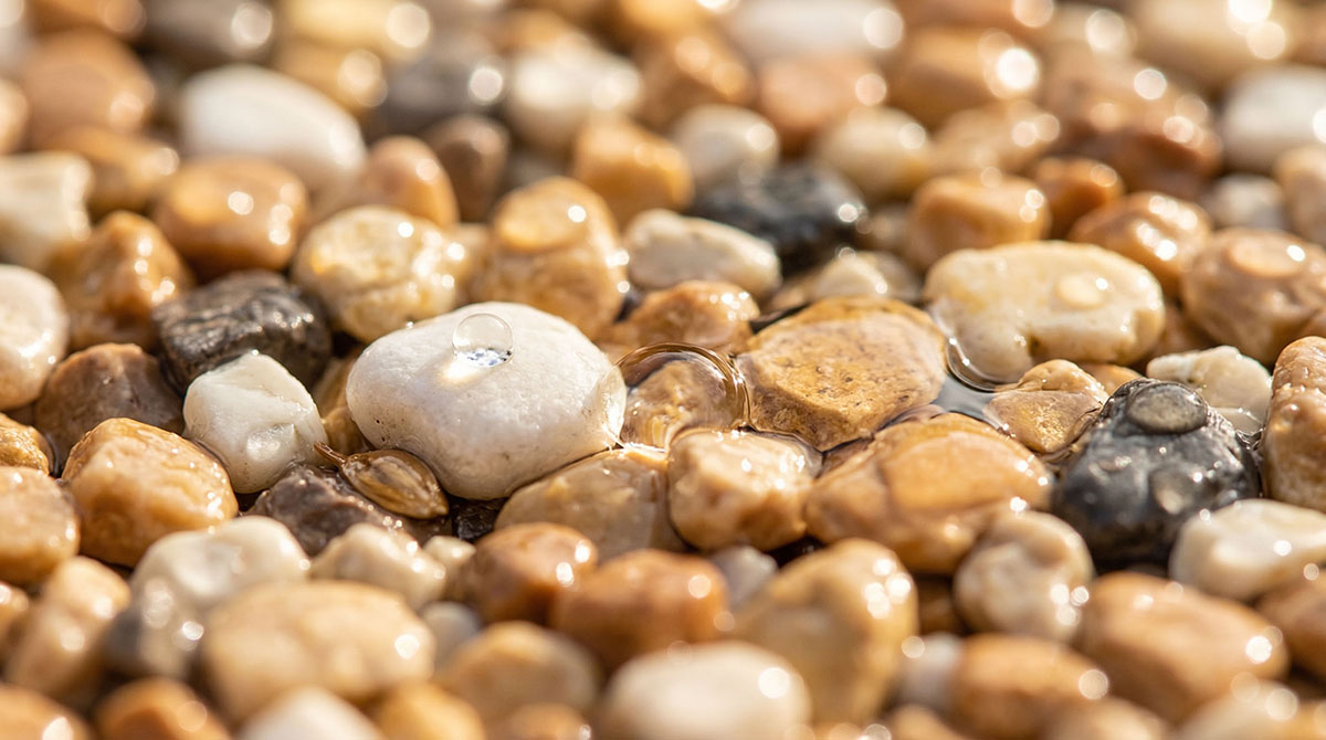 Nahaufnahme von vielfältigen, runden Steinteppich Kieselsteinen in Beige-, Grau- und Brauntönen.