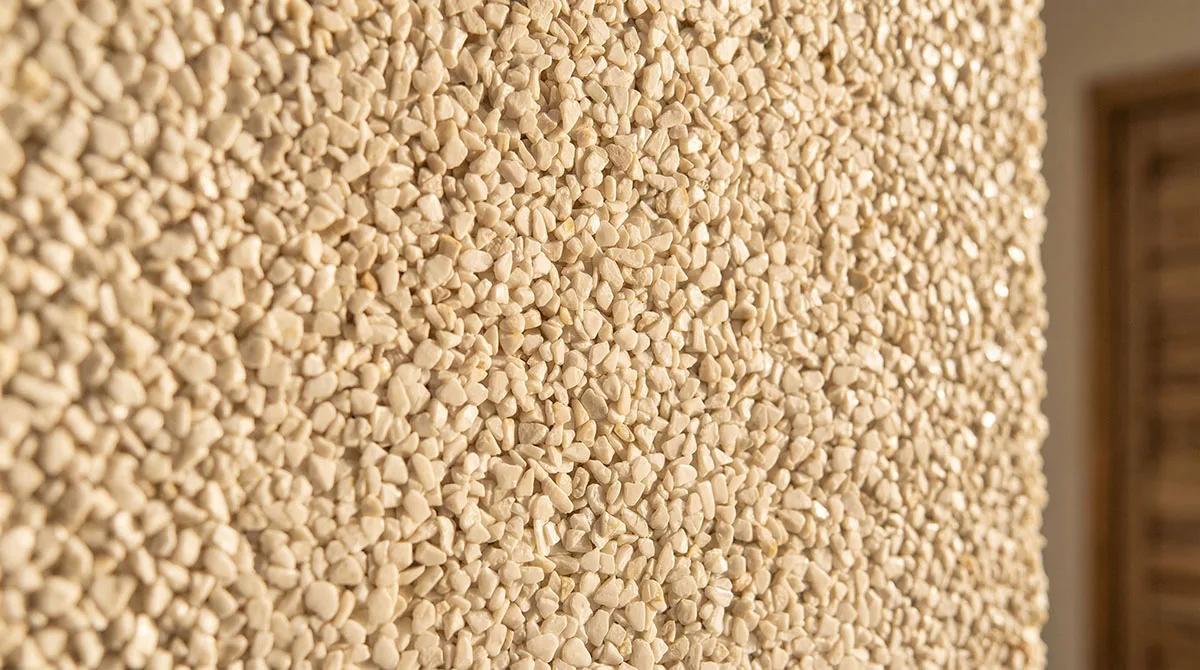 Nahaufnahme eines beigen Steinteppichs mit detailreicher Struktur auf einer Wand
